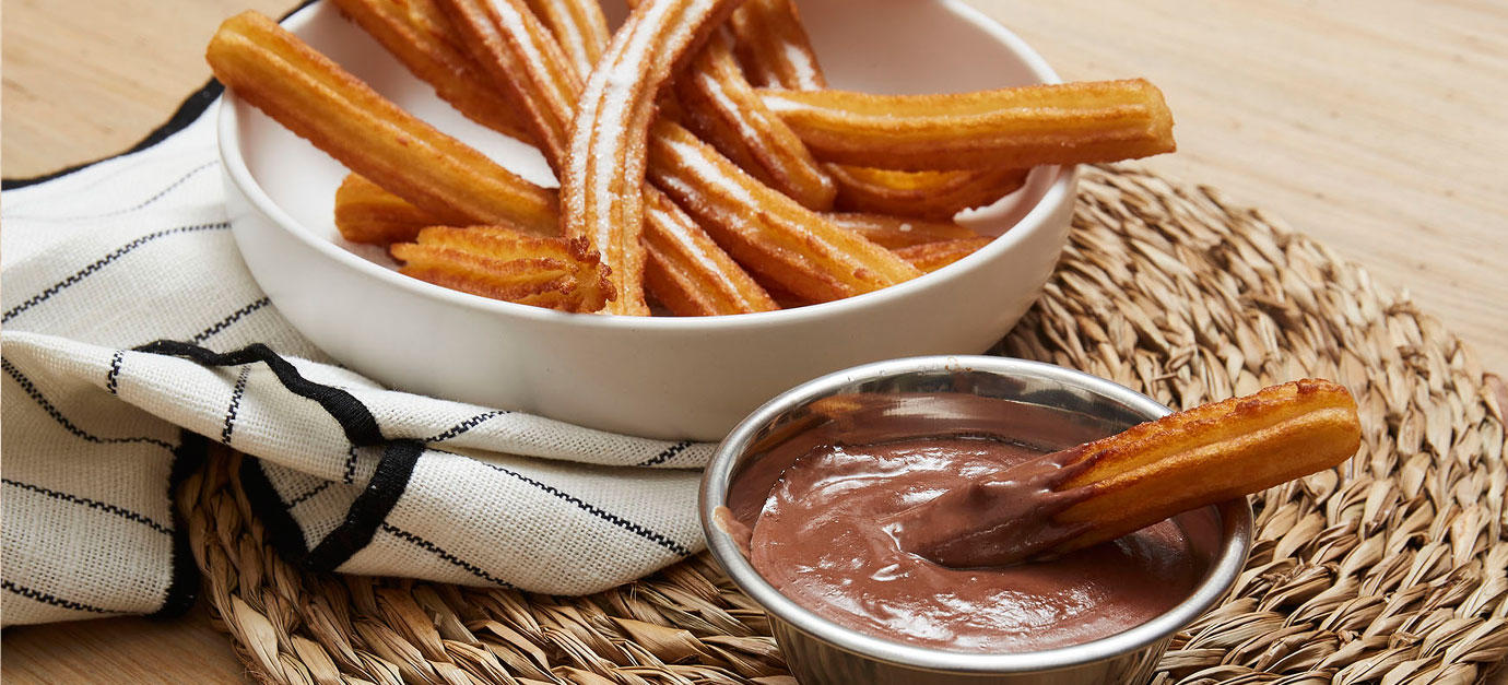 Churros croustillants servis avec une sauce au chocolat chaud.