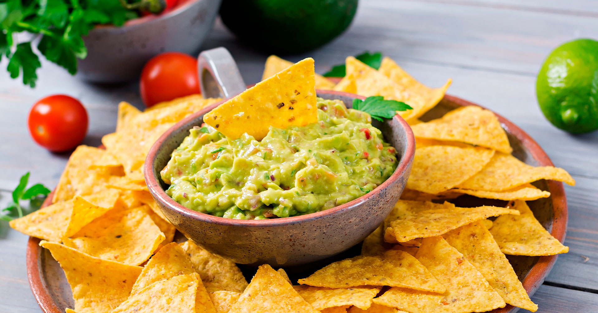 Bol de guacamole frais servi avec des chips de maïs dorées.